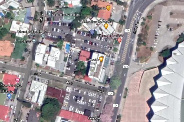 Satellite view of urban blocks showing roads, buildings, and parking lots with overlaid text labels.